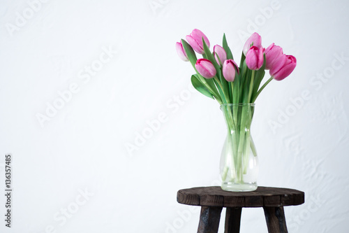 Fototapeta Naklejka Na Ścianę i Meble -  Fresh pink tulip flowers bouquet on shelf in front of swall. View with copy space