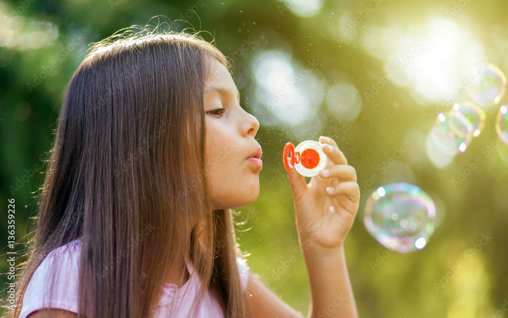 Children girl blowing soap bubbles in outdoor forest Children girl blowing soap bubbles in outdoor forest