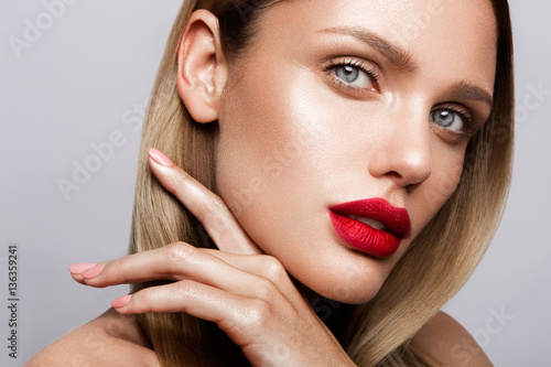 Beautiful young model with red lips and nude manicure