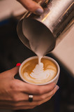 Barista pouring milk in cappuccino coffee in coffeeshop