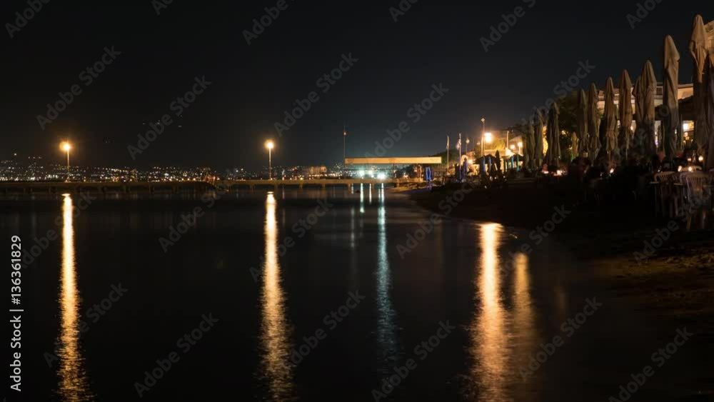 Timelapse shot of nightlife in resort town. People walking in the pier and spending time in beach cafes. Thessaloniki, Greece Timelapse shot of nightlife in resort town. People walking in the pier and spending time in beach cafes. Thessaloniki, Greece