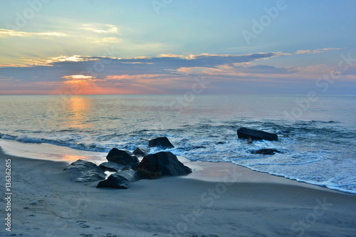Scenic Summer Sunrise Over Rock Jetty at the Shore