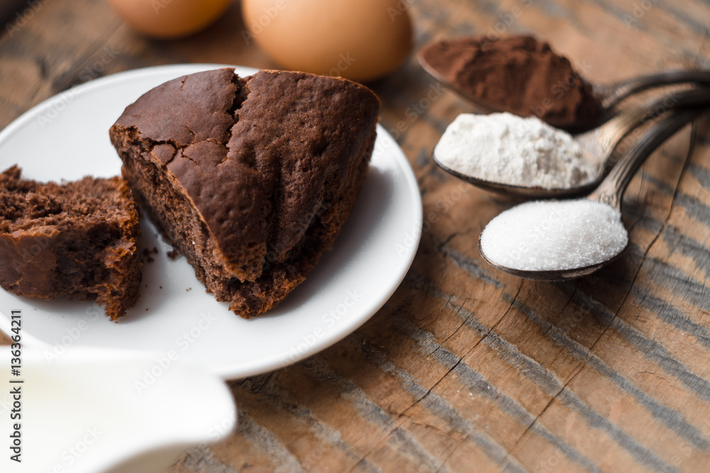 Cake, flour, sugar, cocoa, milk and eggs on a wooden table. Ingredients for cooking. Cake, flour, sugar, cocoa, milk and eggs on a wooden table. Ingredients for cooking.