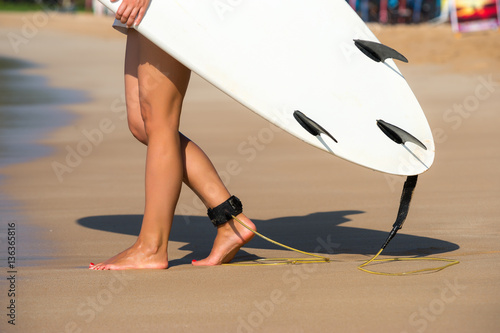 Young beautiful surfer girl on beach with surf board at day brea
