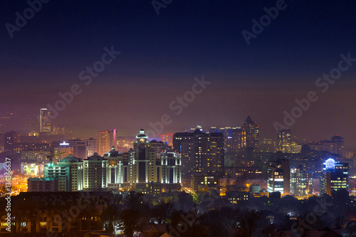 Night over Almaty. Night view of the city of Almaty at night time. Distant buildings are covered with fog.