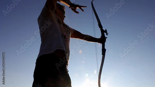 Silhouette of man using bow and arrow