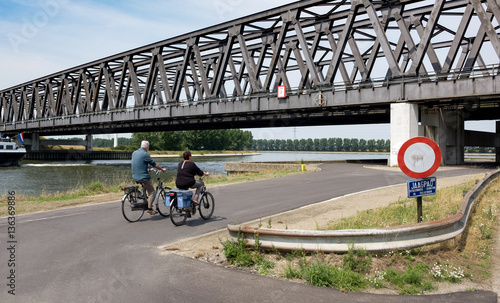 Two cyclists riding underneath Noordlandbrug in the Port of Antwerp, Belgium. photo