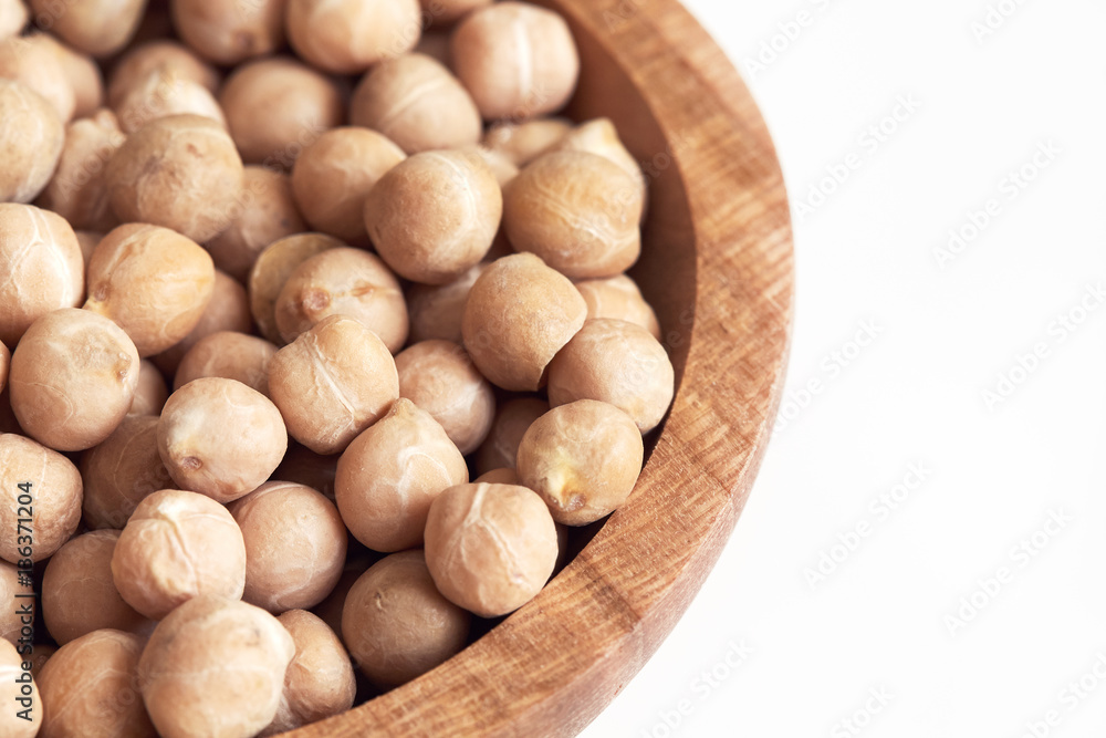 Raw uncooked chickpeas (garbanzo beans) in wooden bowl on white background. Copy space Raw uncooked chickpeas (garbanzo beans) in wooden bowl on white background. Copy space