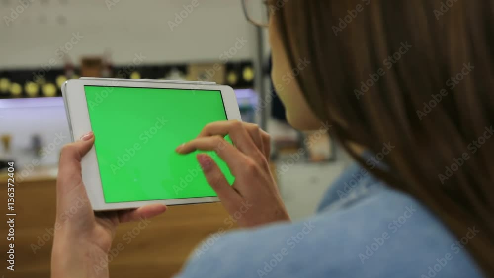 Young attractive woman using tablet with green screen sitting in the cafe, swipe pictures, news. Close-up. Chroma key Young attractive woman using tablet with green screen sitting in the cafe, swipe pictures, news. Close-up. Chroma key