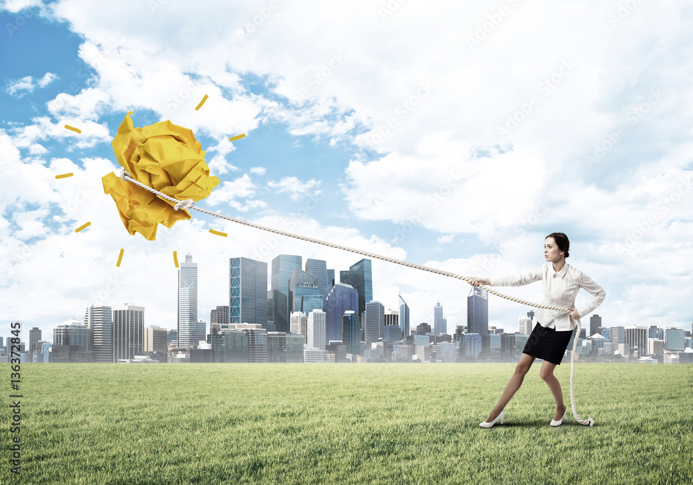 Businesswoman pulling paper ball with rope and making it raise up