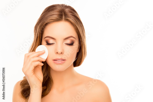 Pretty woman washing off makeup with cotton pad on white backgro