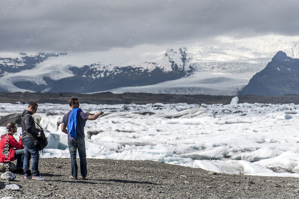 Iceland men standing at glacier lake Jokulsarlon glacial lagoon nature snow landscape Vatnajokull