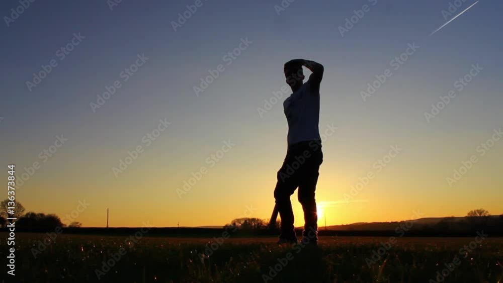 Silhouette of baseball player hitting ball, sunset Silhouette of baseball player hitting ball, sunset