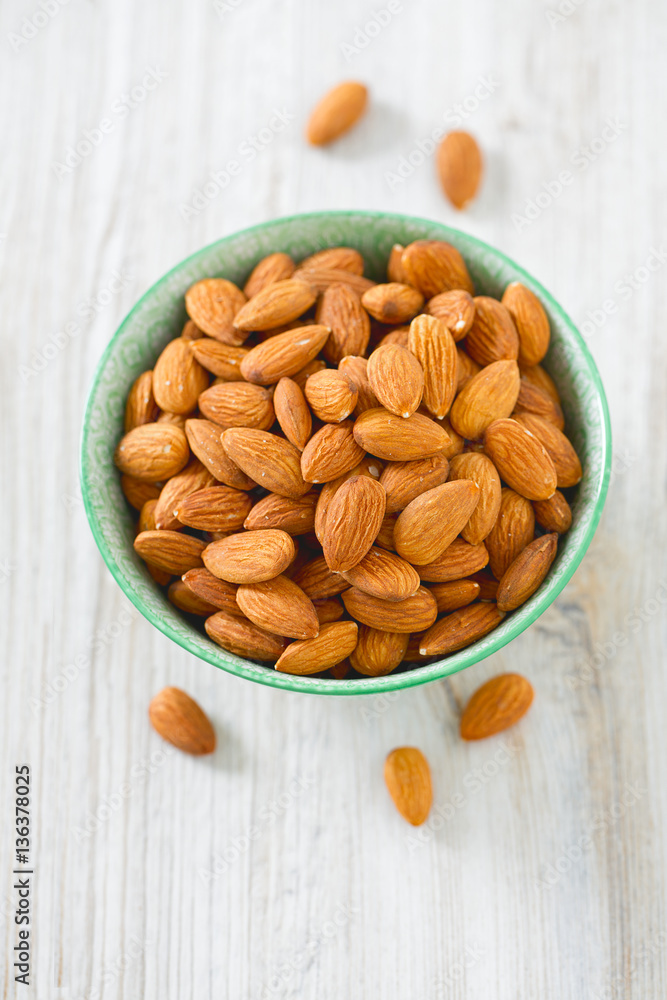 almonds in a bowl on wooden surface almonds in a bowl on wooden surface