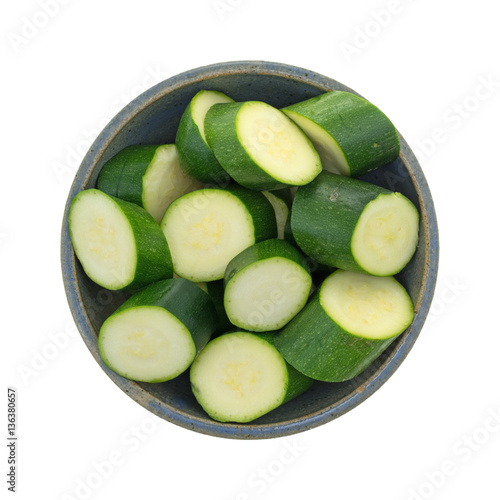 Top view of sliced Italian squash in an old stoneware bowl isolated on a white background.