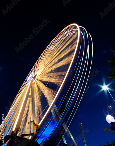 A vibrant Ferris wheel with vivid colours  photographed outdoor with long exposure at twilight. Slow shuts speed motion blur.