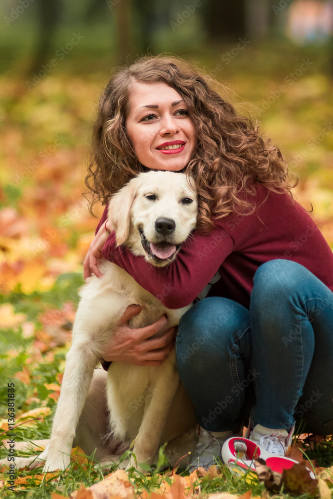 Close-up of curly woman sitting with her dog in autumn leaves outdoors Close-up of curly woman sitting with her dog in autumn leaves outdoors