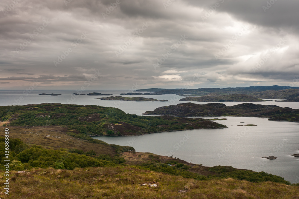 Assynt Peninsula, Scotland - June 7, 2012: Under dark cloudy sky aerial view on Loch Ardhair with intrusion of the ocean in the wild landscape of hills, mountains, bare land, small and larger islands.