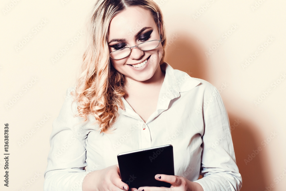 Blonde woman in glasses holding a tablet and smiling at the background willow Blonde woman in glasses holding a tablet and smiling at the background willow