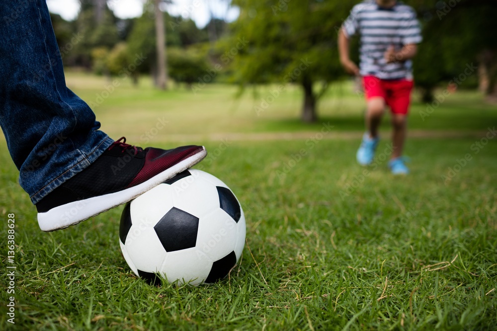 Low section of father and son playing football Low section of father and son playing football