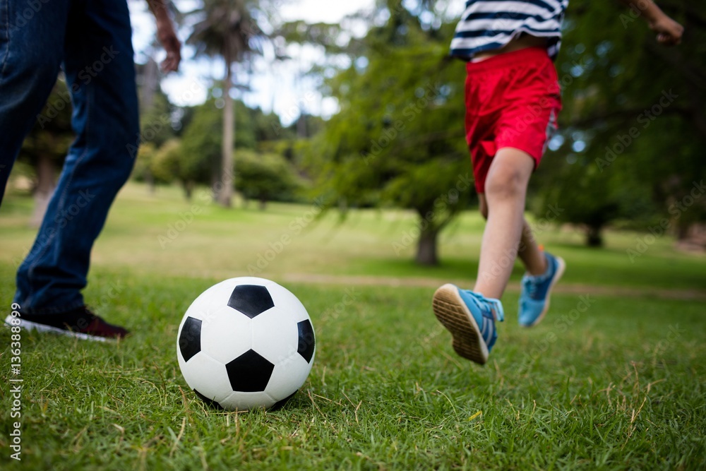 Low section of father and son playing football