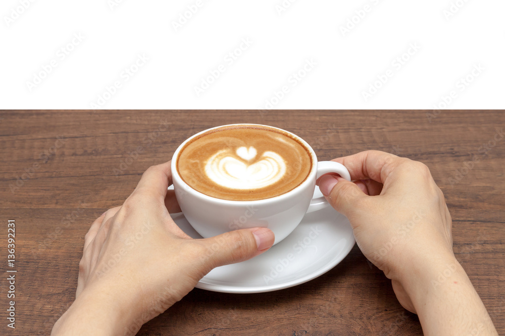 Hand holding coffee cup of latte art on wooden table with white