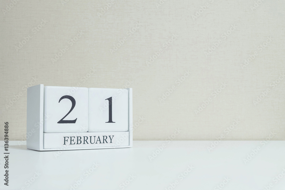 Closeup white wooden calendar with black 21 february word on blurred white wood desk and cream color wallpaper in room textured background with copy space in selective focus at the calendar Closeup white wooden calendar with black 21 february word on blurred white wood desk and cream color wallpaper in room textured background with copy space in selective focus at the calendar