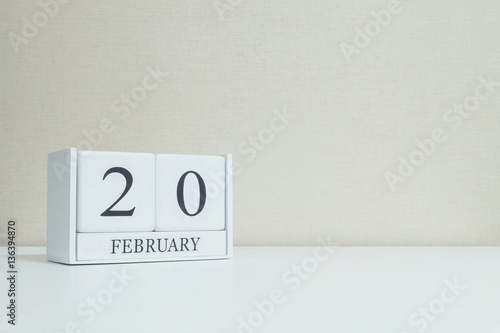 Closeup white wooden calendar with black 20 february word on blurred white wood desk and cream color wallpaper in room textured background with copy space in selective focus at the calendar © kenkuza