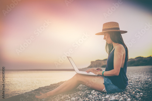 young beautiful woman with long dark hair sitting on the beach a