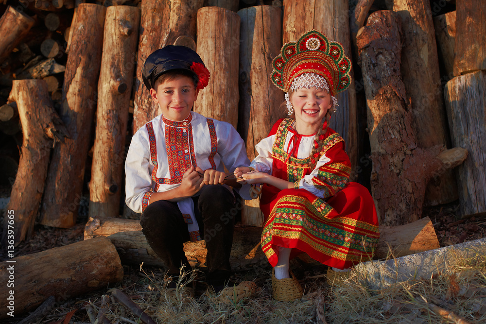 Two Russian kids in russian folk costume boy and girl playing together and emotionally smiling