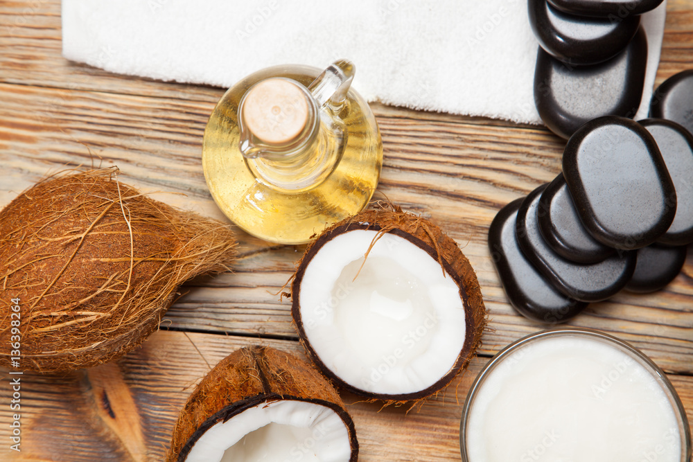 Oil, coconut and stones for a massage on wooden background Oil, coconut and stones for a massage on wooden background