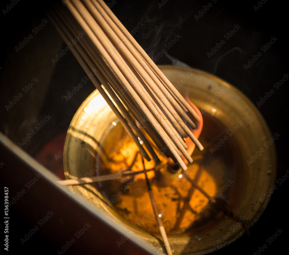 Photo of Smoke Sticks Burning Out in Gold Bowl with Fire. Asian Religion Aroma Sticks for Praying