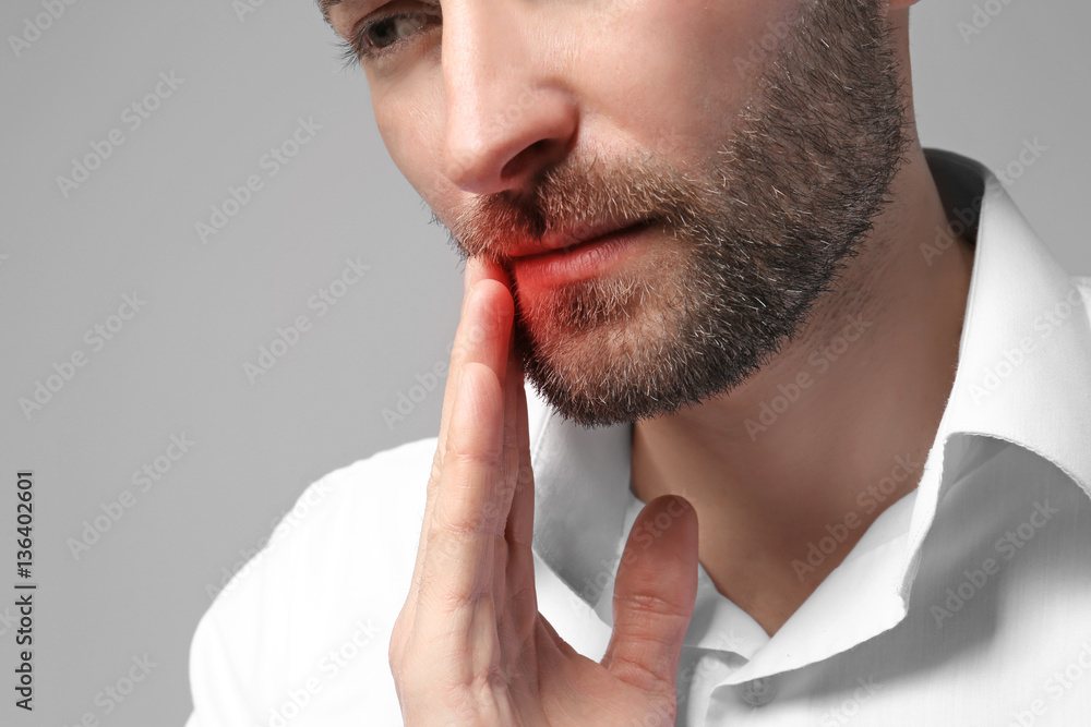 Man suffering from tooth pain on gray background. Health care concept Man suffering from tooth pain on gray background. Health care concept