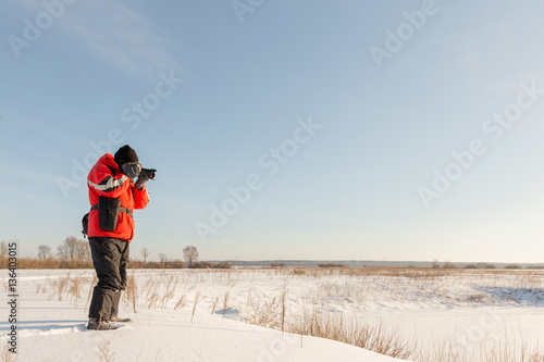 photographer takes winter landscape at dawn in the bitter cold.