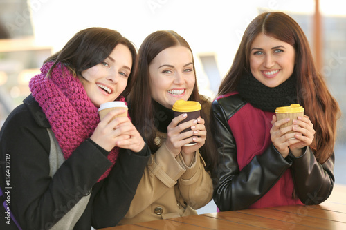 Cheerful young women drinki...
