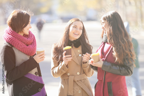 Cheerful young women drinki...