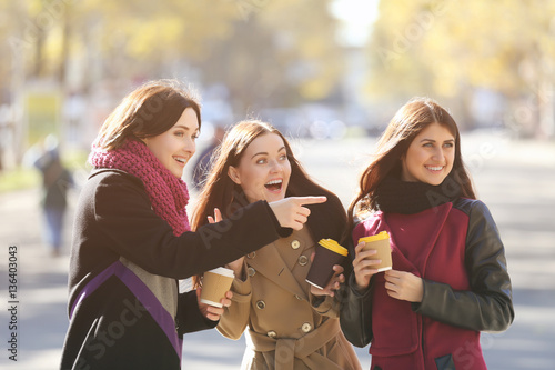 Cheerful young women drinki...