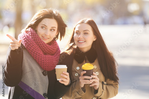 Cheerful young women drinki...