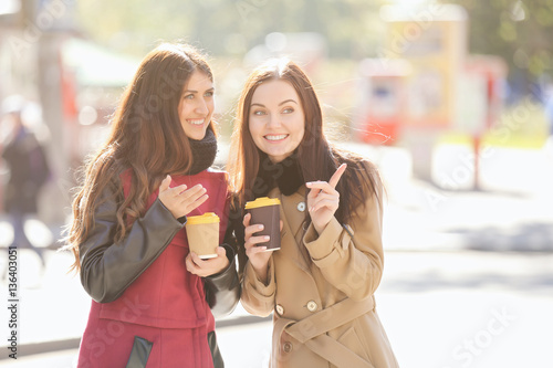 Cheerful young women drinki...