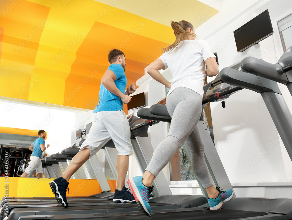 Fototapeta Young people running on treadmills in gym