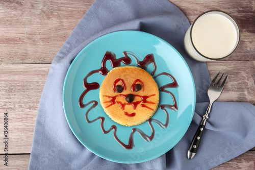 Funny pancake for kids breakfast, on wooden background
