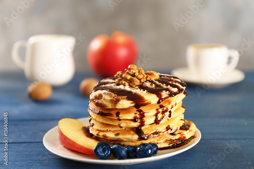 Delicious pancakes with chocolate syrup  blueberry and sliced apple on blue wooden table