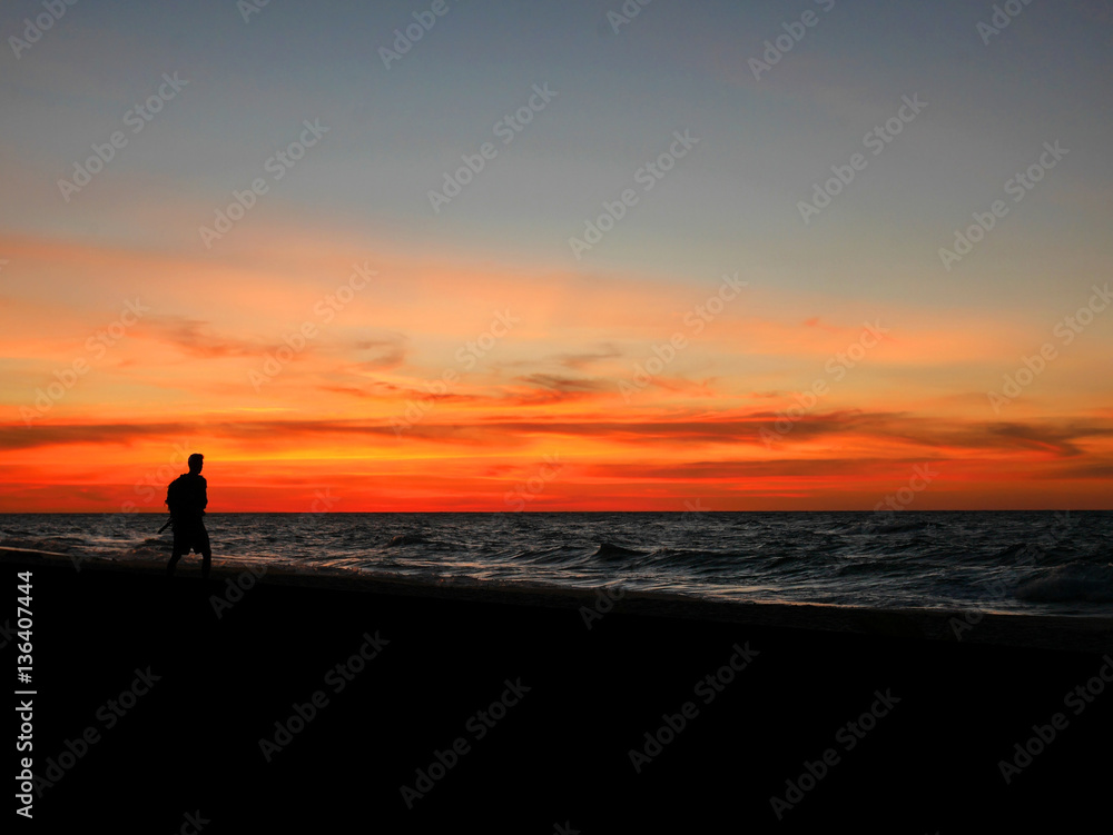 Silhouette man walking on sunset beach