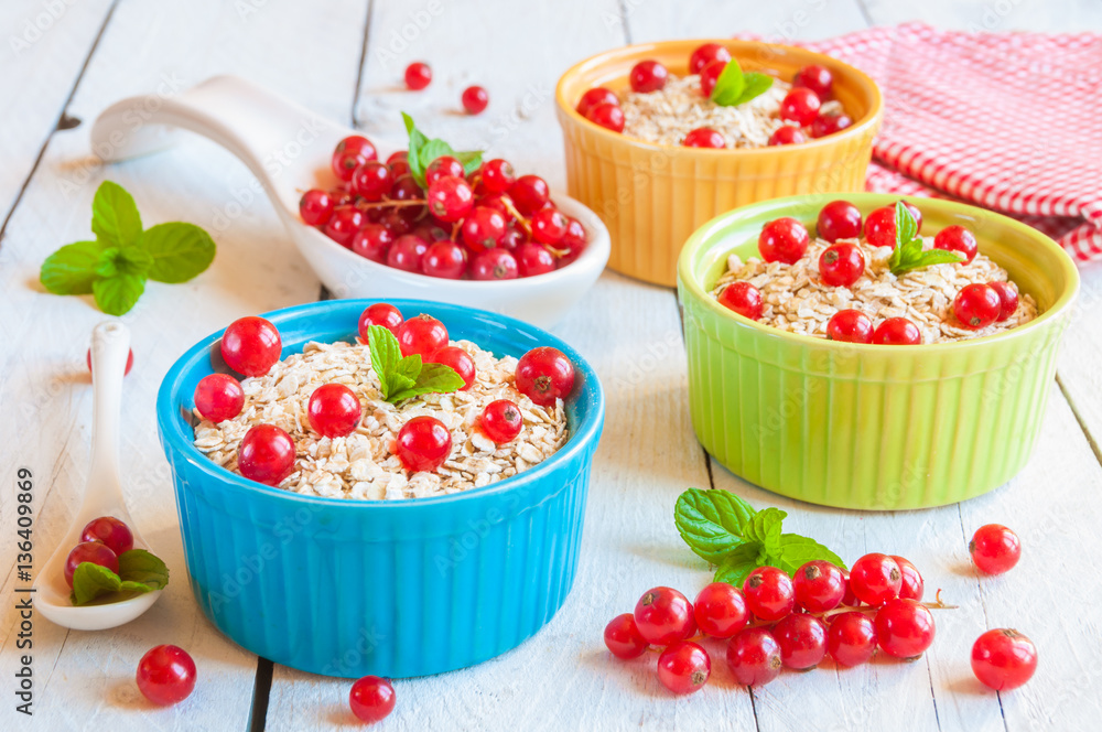 Oat flakes with red currant in colorful bowls Oat flakes with red currant in colorful bowls