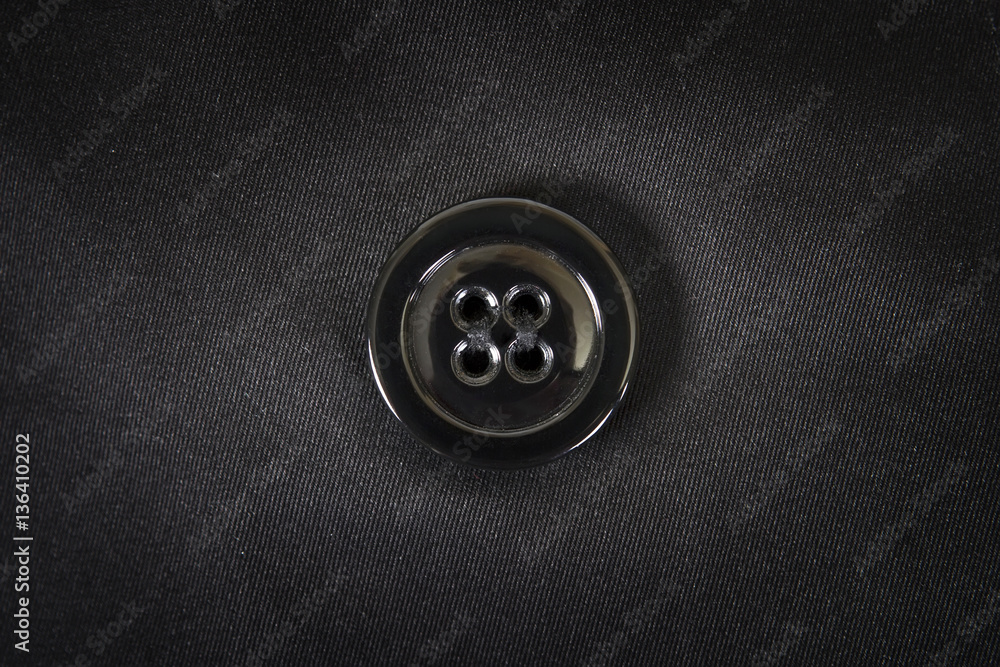 Black plastic button is sewn on black fabric Black plastic button is sewn on black fabric