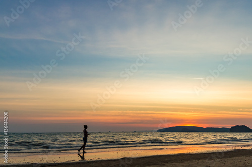 Young woman walking on the beach against the backdrop of a beautiful sunset