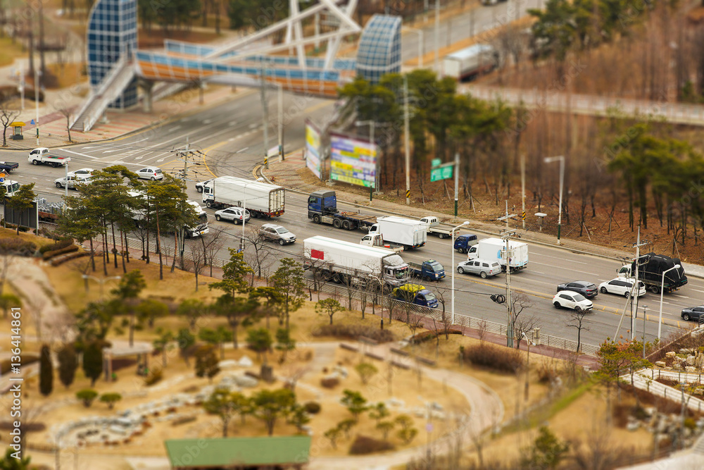 Aerial view of the highway and park. On the road a lot of cars. Tilt Shift effect