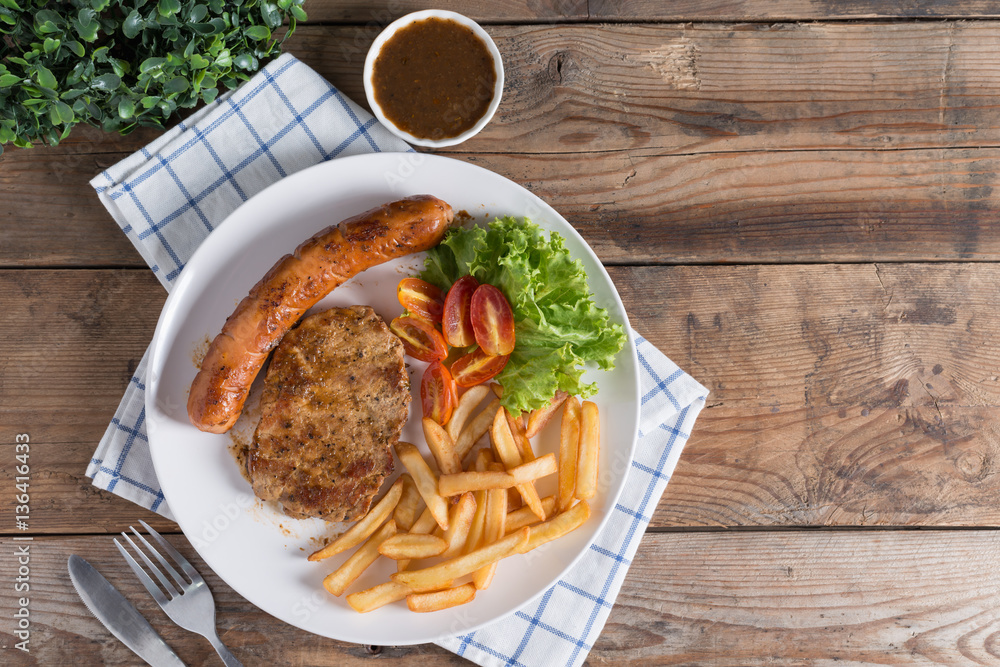 Roasted beef meat steak and sausage with french fries. Top view. Roasted beef meat steak and sausage with french fries. Top view.