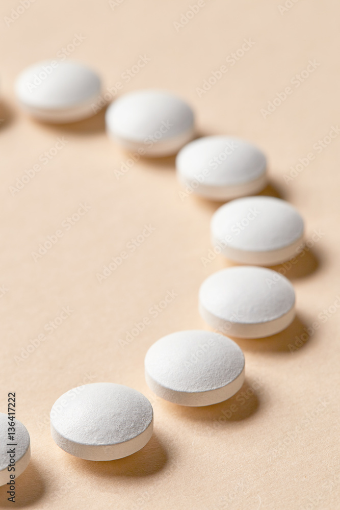 white pills on beige background white pills on beige background