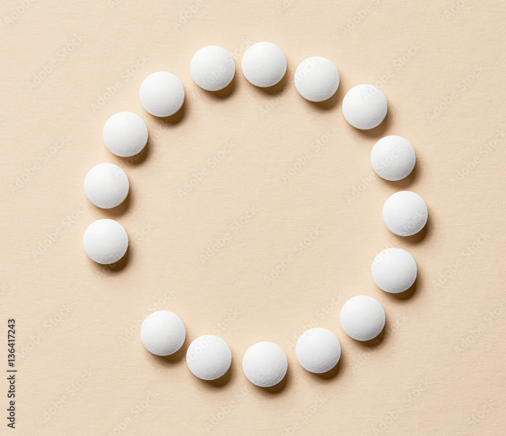 white pills on beige background white pills on beige background